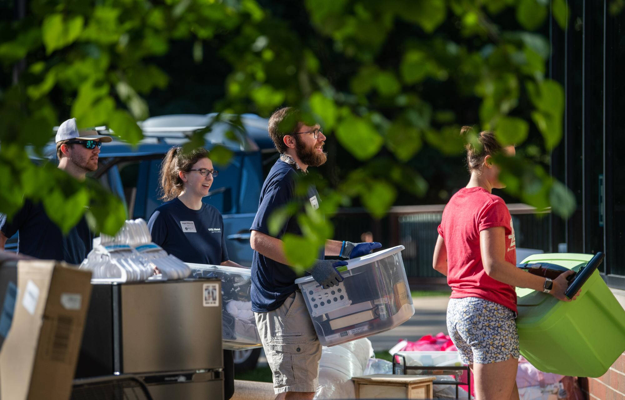 Individuals carrying totes into campus housing